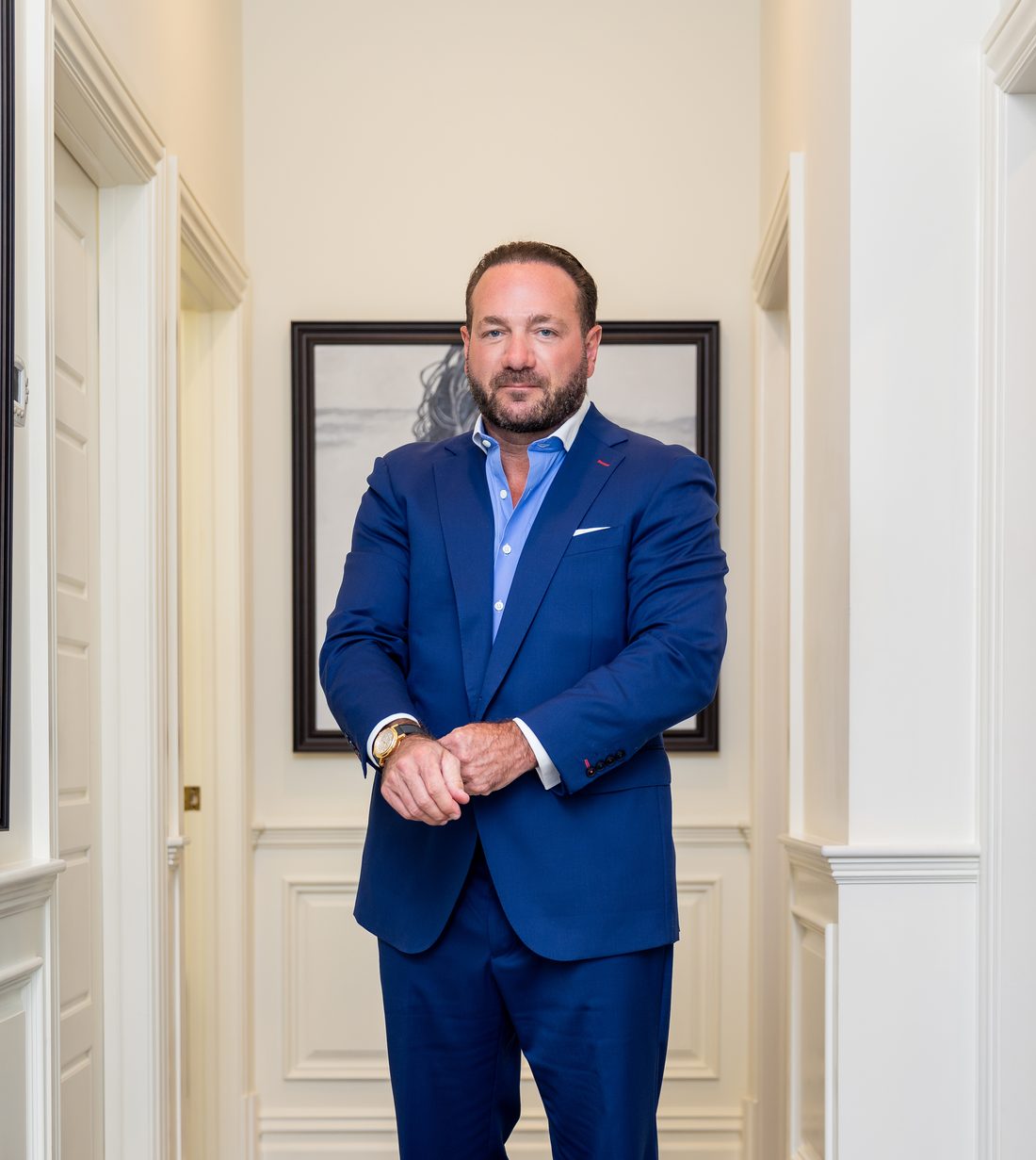 Dr. Joseph A. Racanelli standing in the art-lined hallway of his plastic surgery practice